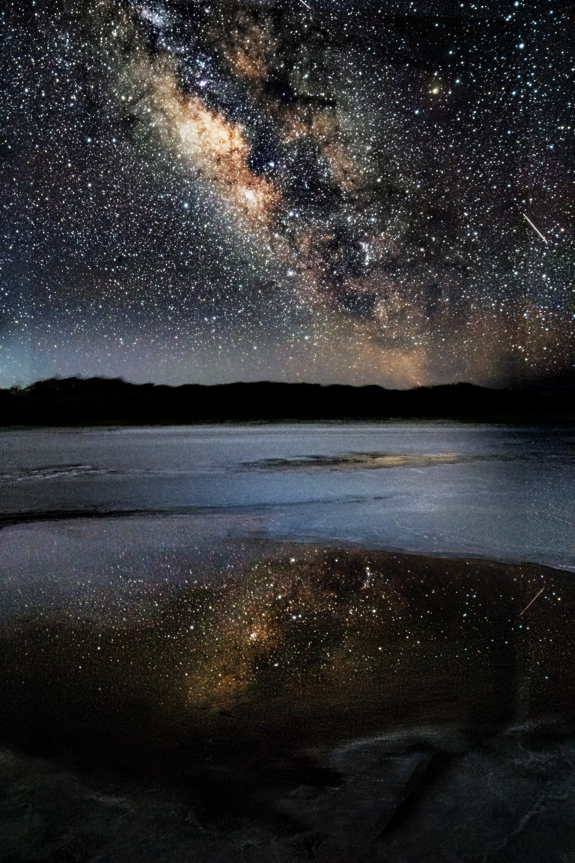 The night sky filled with stars being reflected off a body of water